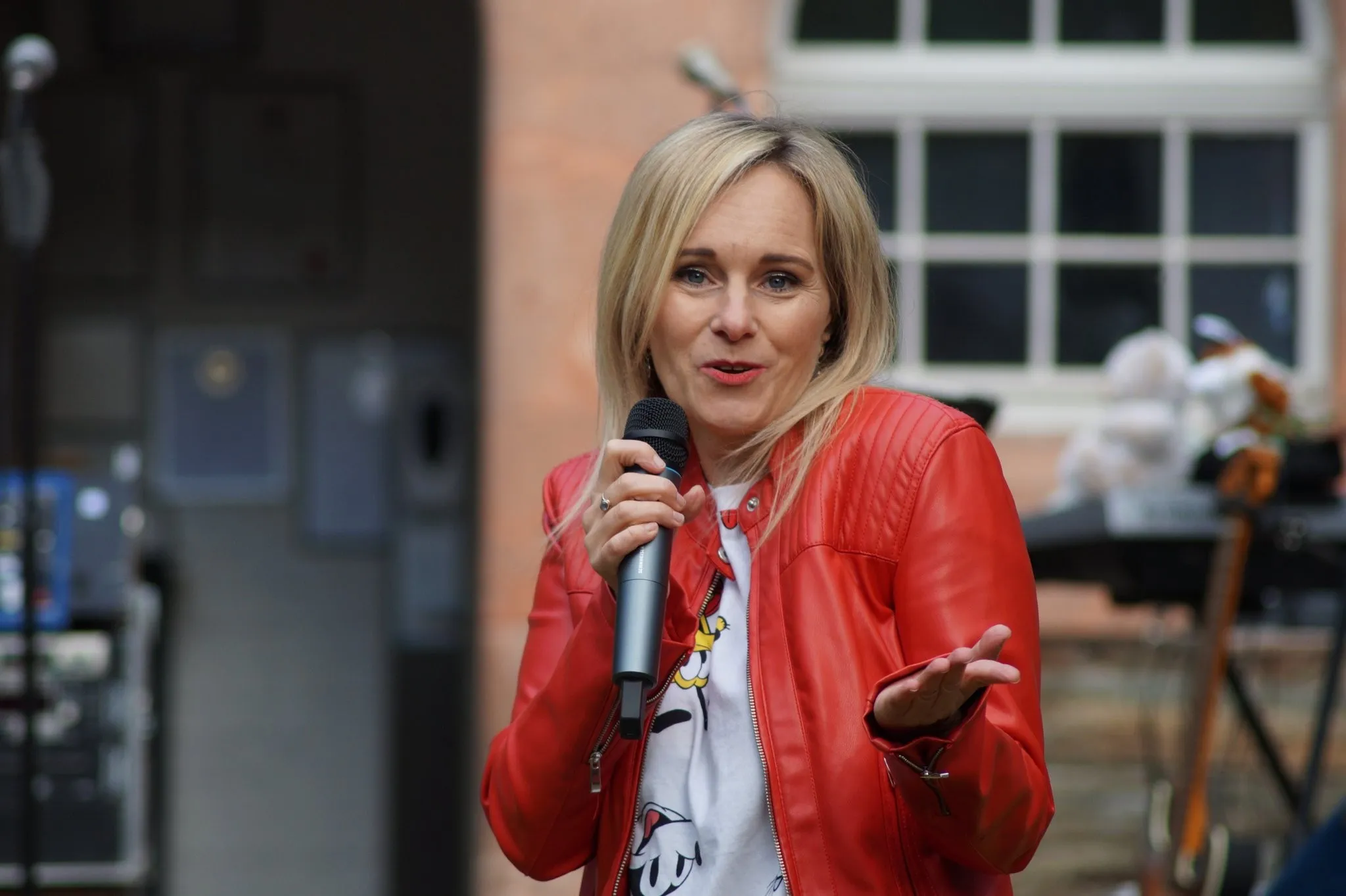 Susanne Petzold in roter Lederjacke mit Mikrofon